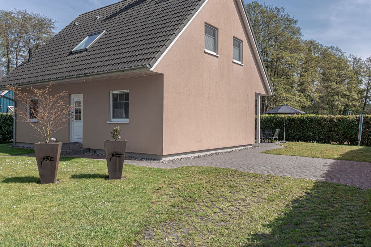 Das Ferienhaus von der Straßenseite, davor eine Rasenfläche mit gepflastertem Weg