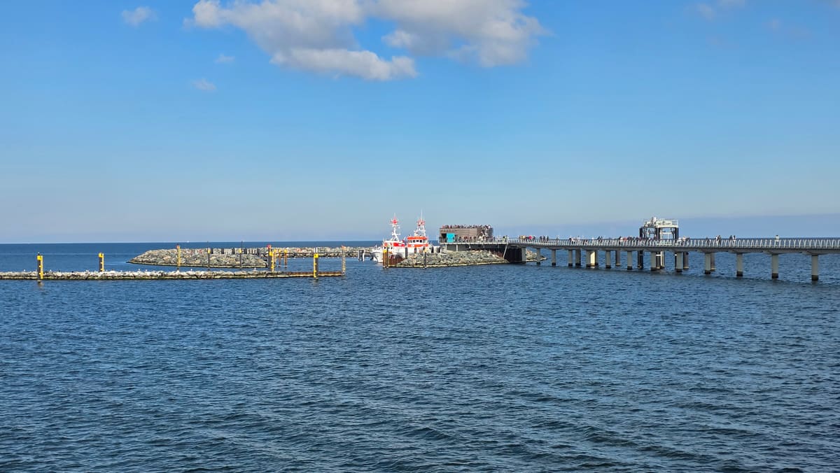 Hafenkopf am Ende der Seebrücke mit Anleger und einem Schiff, davor die offene Ostsee